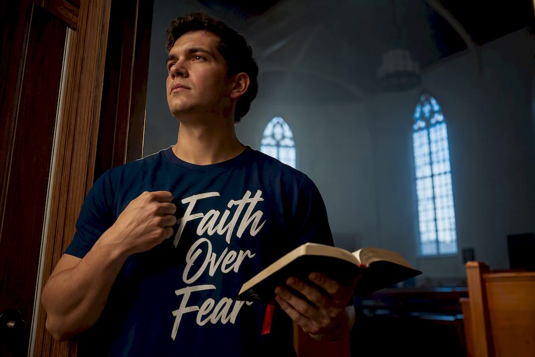 Believer holding Bible in Faith Over Fear shirt
